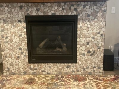 Modern stone fireplace with black insert remodeled work by ProWork Builders.